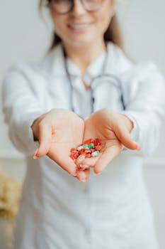 A female healthcare professional with a stethoscope presenting a handful of pills.
