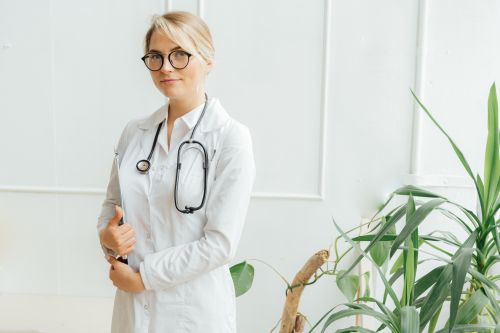 Free Confident female doctor standing with stethoscope in a bright clinic setting. Stock Photo
