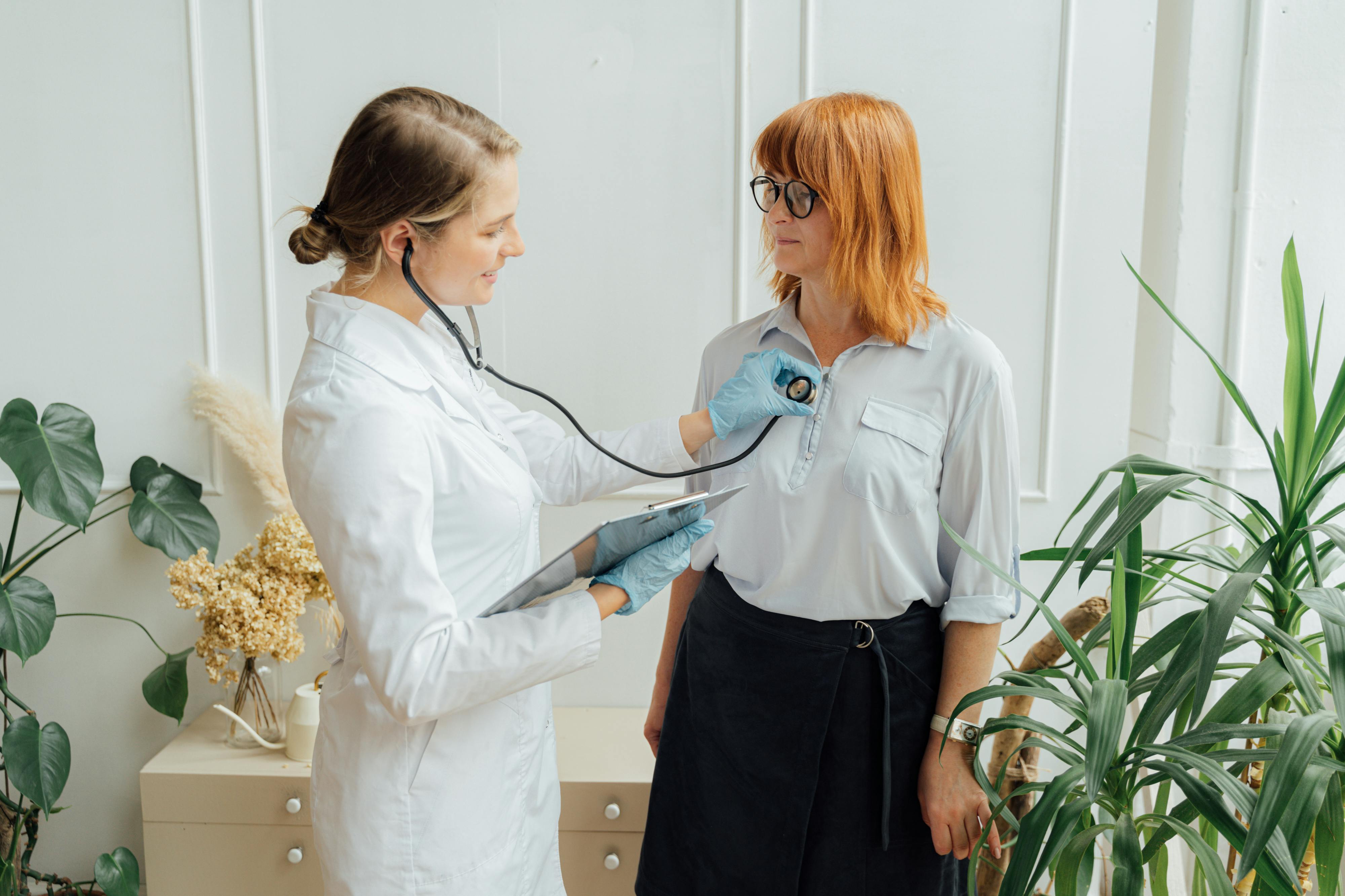 A doctor examines her patient with a stethoscope.