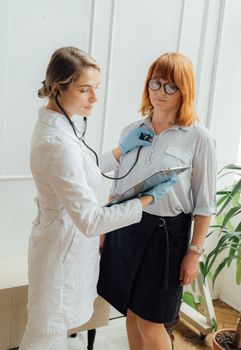 在明亮的诊所里，女医生用听诊器检查病人的心跳