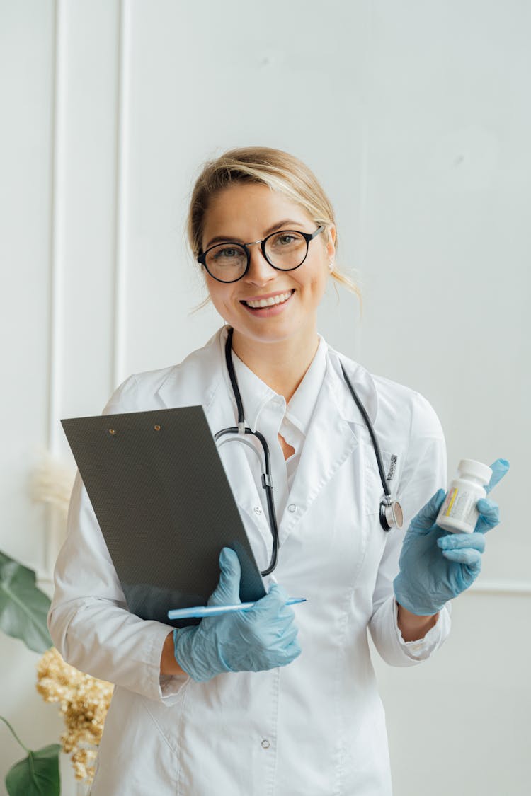 Doctor Wearing Eyeglasses Holding Medicine And Clipboard