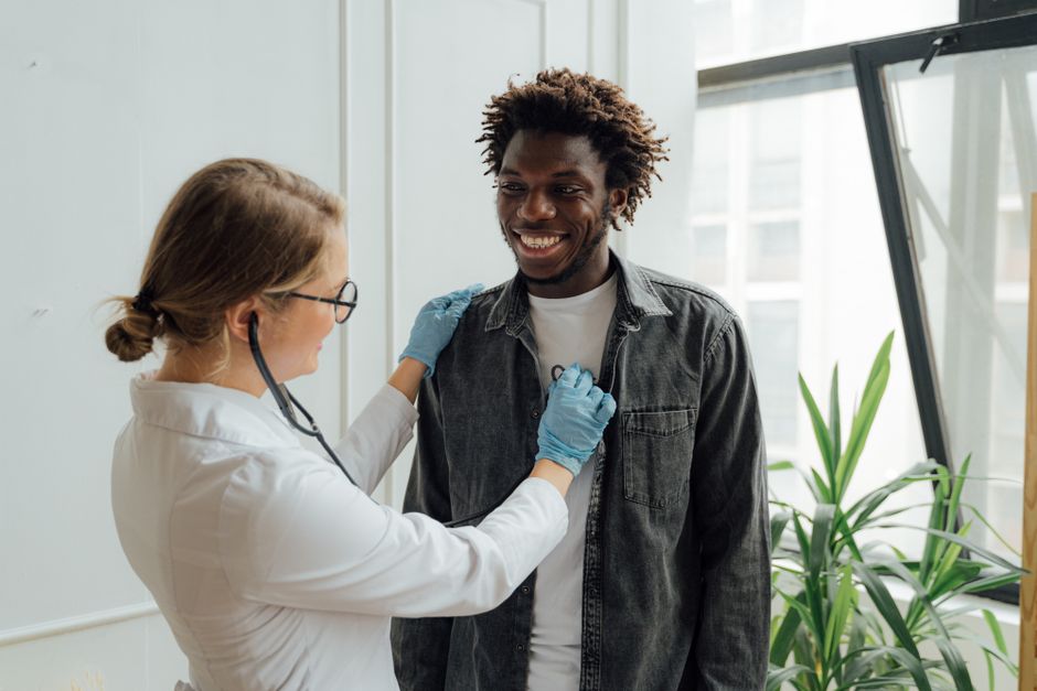 A relaxed man at a routine health checkup by age, talking with his doctor in a bright clinic