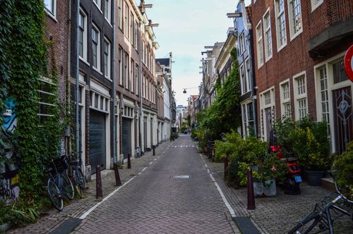 Free Narrow paved street between small aged typical residential buildings against cloudy sky in city Stock Photo