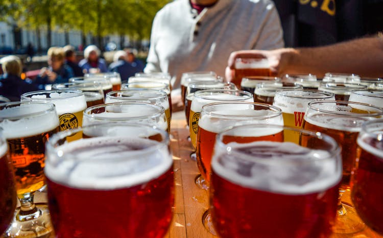 Faceless Tourists Drinking Beer In Street Bar On Sunny Day