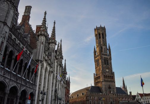 Low angle view of the Belfry of Bruges against a clear blue sky, showcasing Gothic architecture.