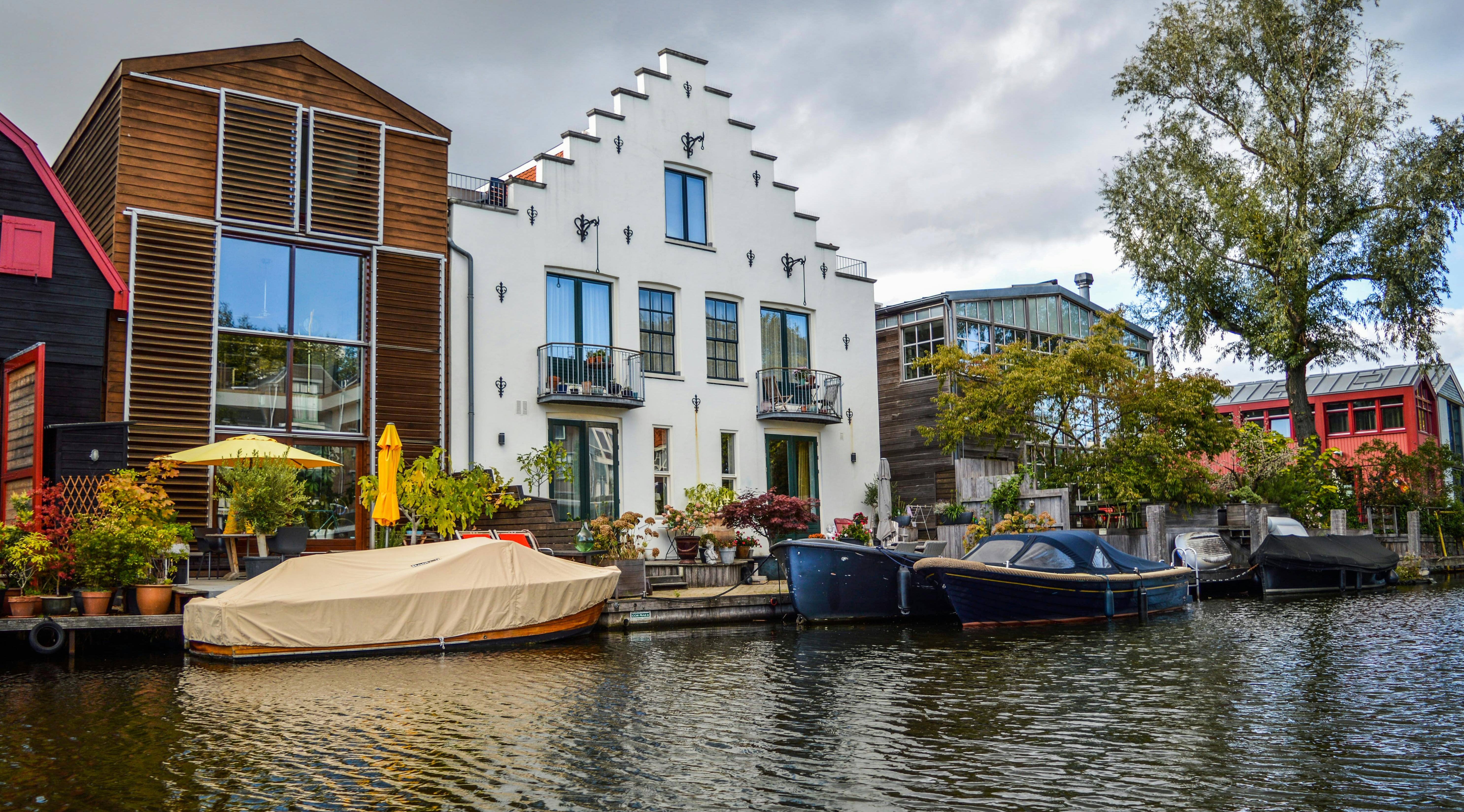 Charming riverside view with modern houses and moored boats, reflecting architectural elegance.