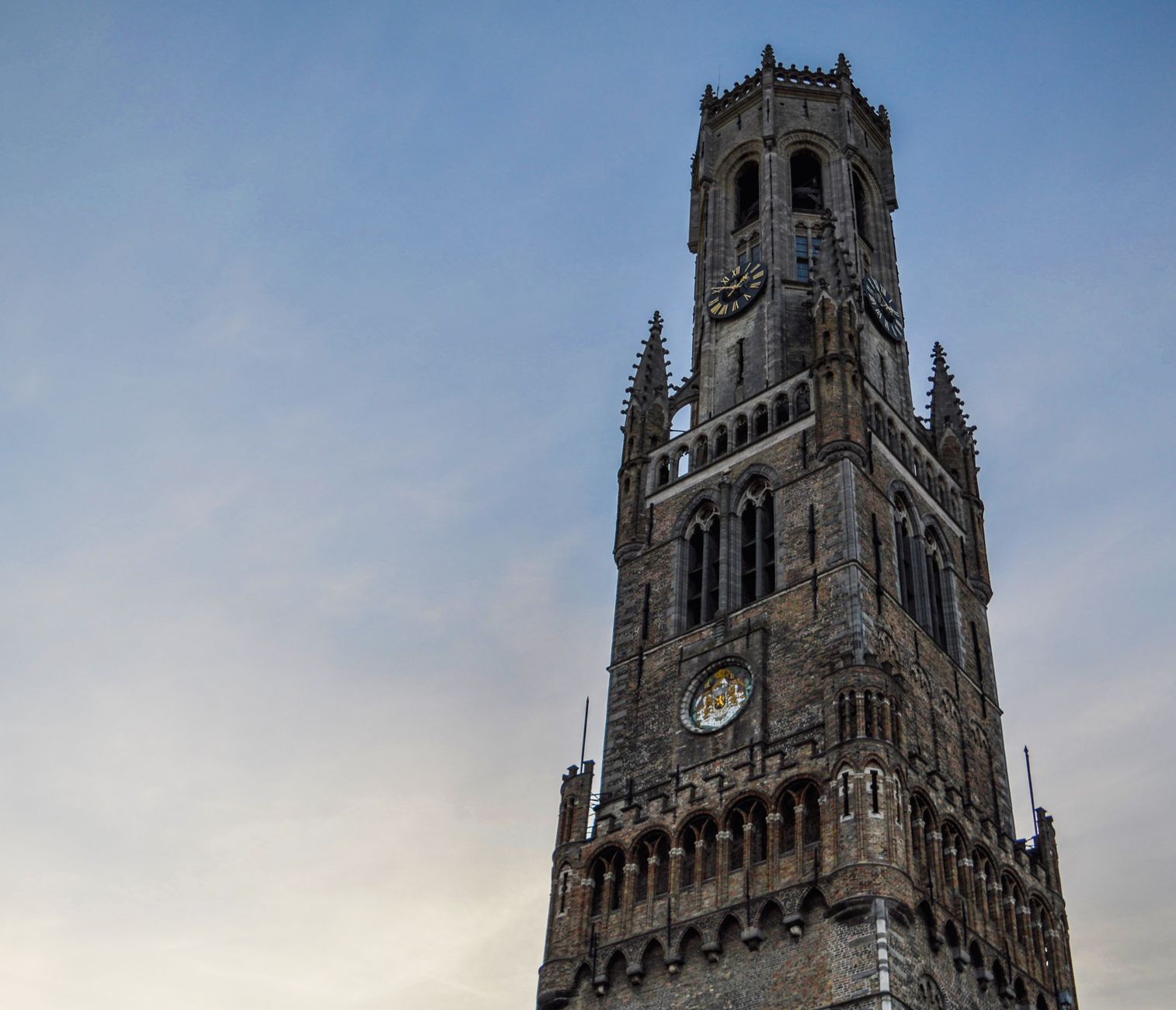 Low-angle view of the iconic Belfry of Bruges, showcasing its Gothic architecture under a blue sky.