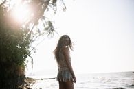 Woman with Curly Hair Standing under a Tree on a Beach
