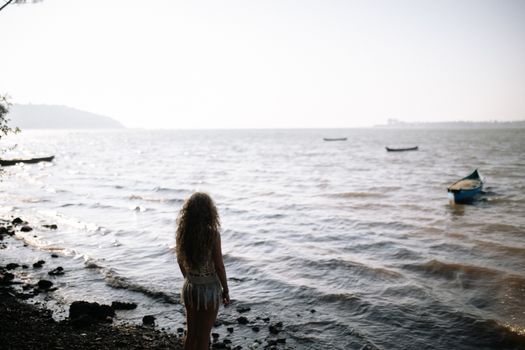 在宁静的海滩上，一名女子凝视着漂浮在海面上的船只