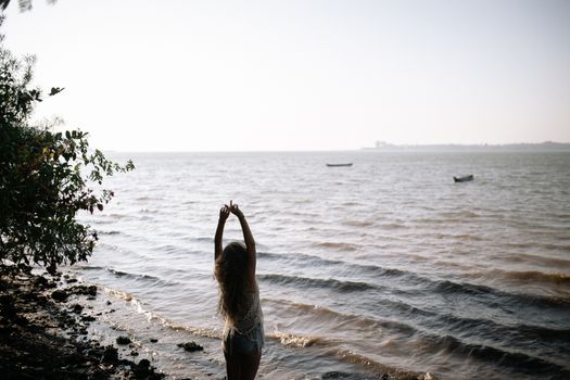 海边，一名女子举起双臂，享受着宁静