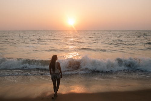Woman Standing on a Seashore at Sunset 