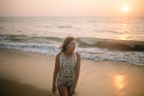 Woman in White Tank Top Standing on Beach