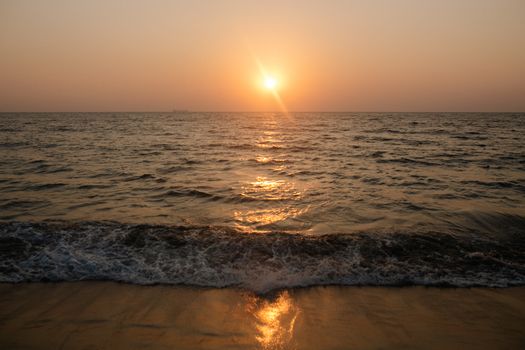 宁静的日落下，温柔的波浪轻抚着沙质海岸