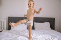 Topless Boy in White and Black Shorts on White Bed