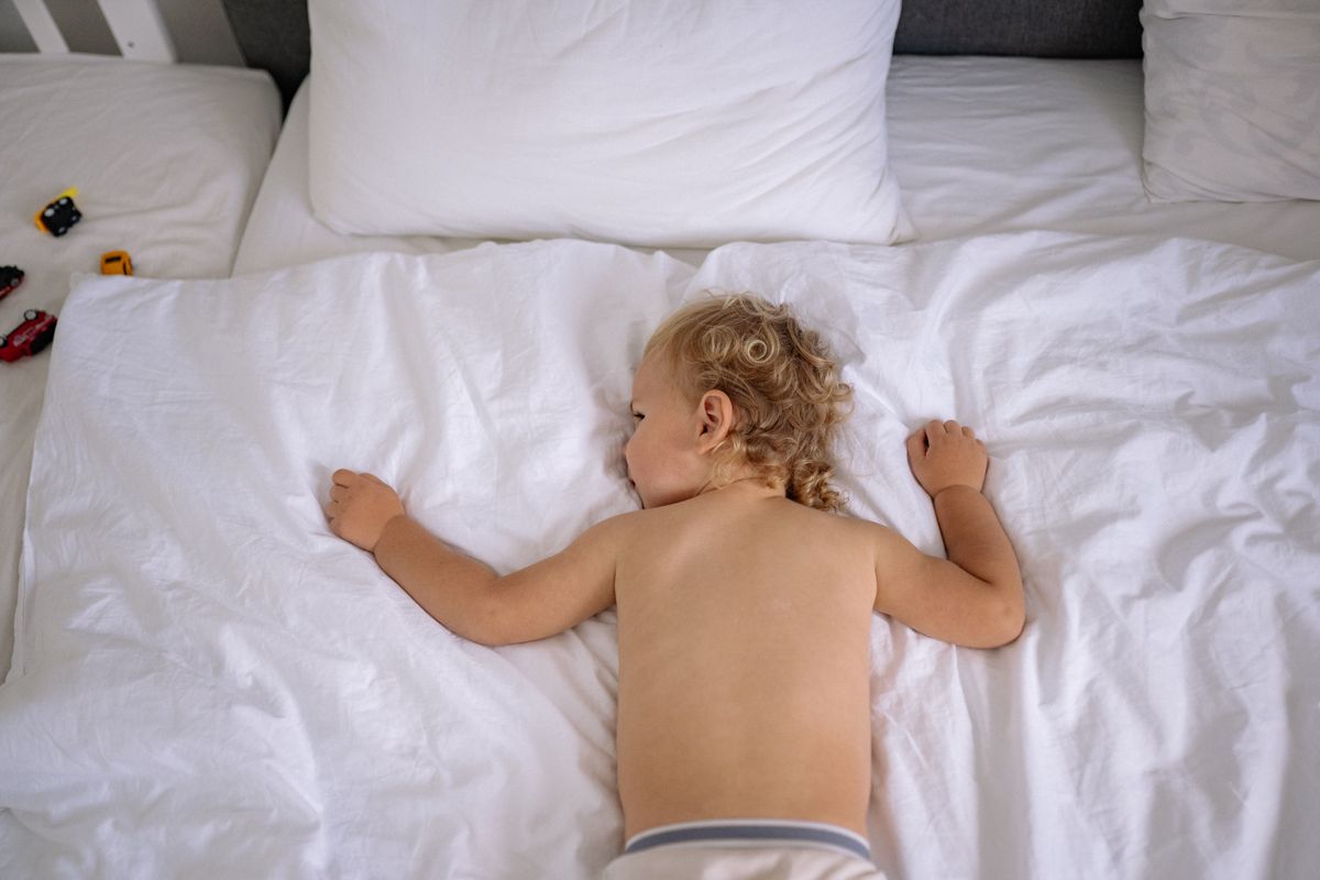 Toddler sleeping peacefully on a white bed
