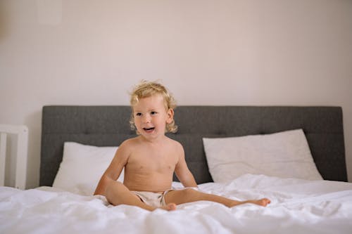 Free Smiling Child Sitting on a Bed Stock Photo
