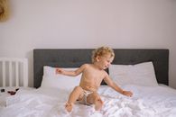 幼儿在光线充足的卧室里，舒适地躺在床上快乐地玩耍