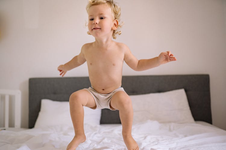 A Child Jumping On The Bed 