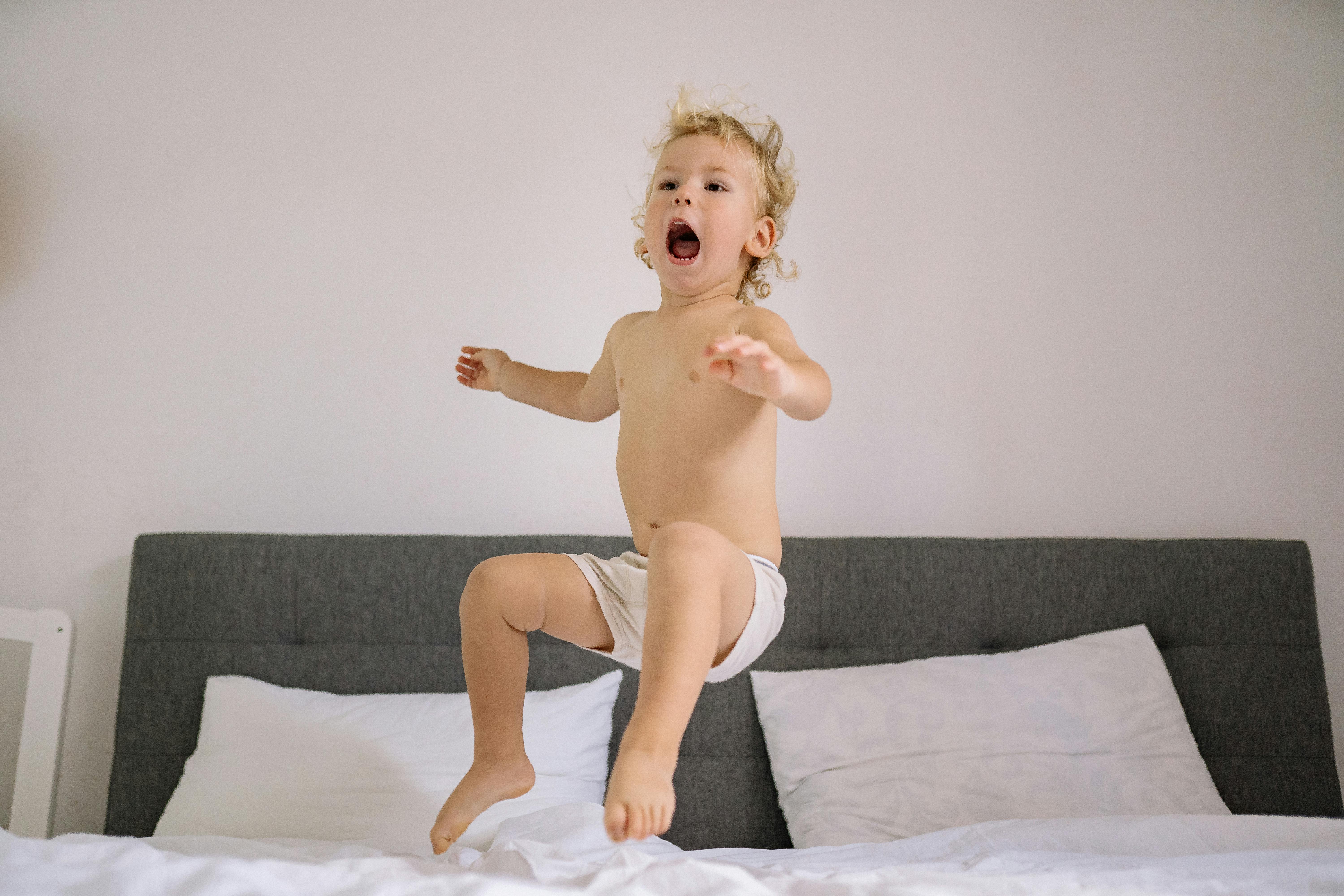 cute child jumping on bed at home