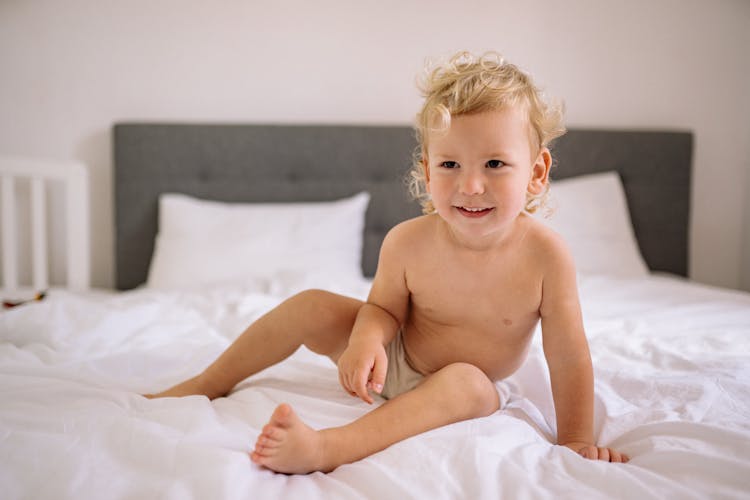 Happy Toddler Sitting On Bed