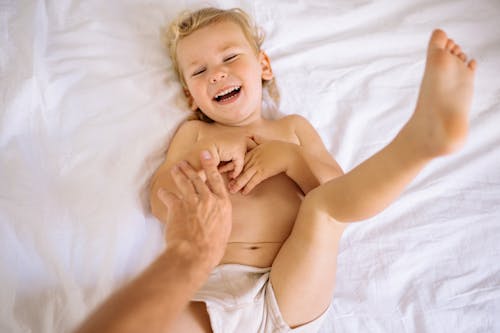 Free Blonde Boy Lying on a Bed and Giggling Stock Photo