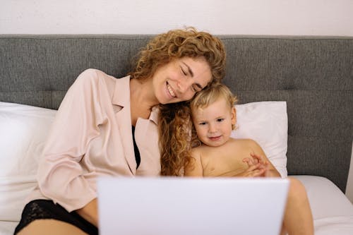 Happy Mother and Child in Bed Watching Computer