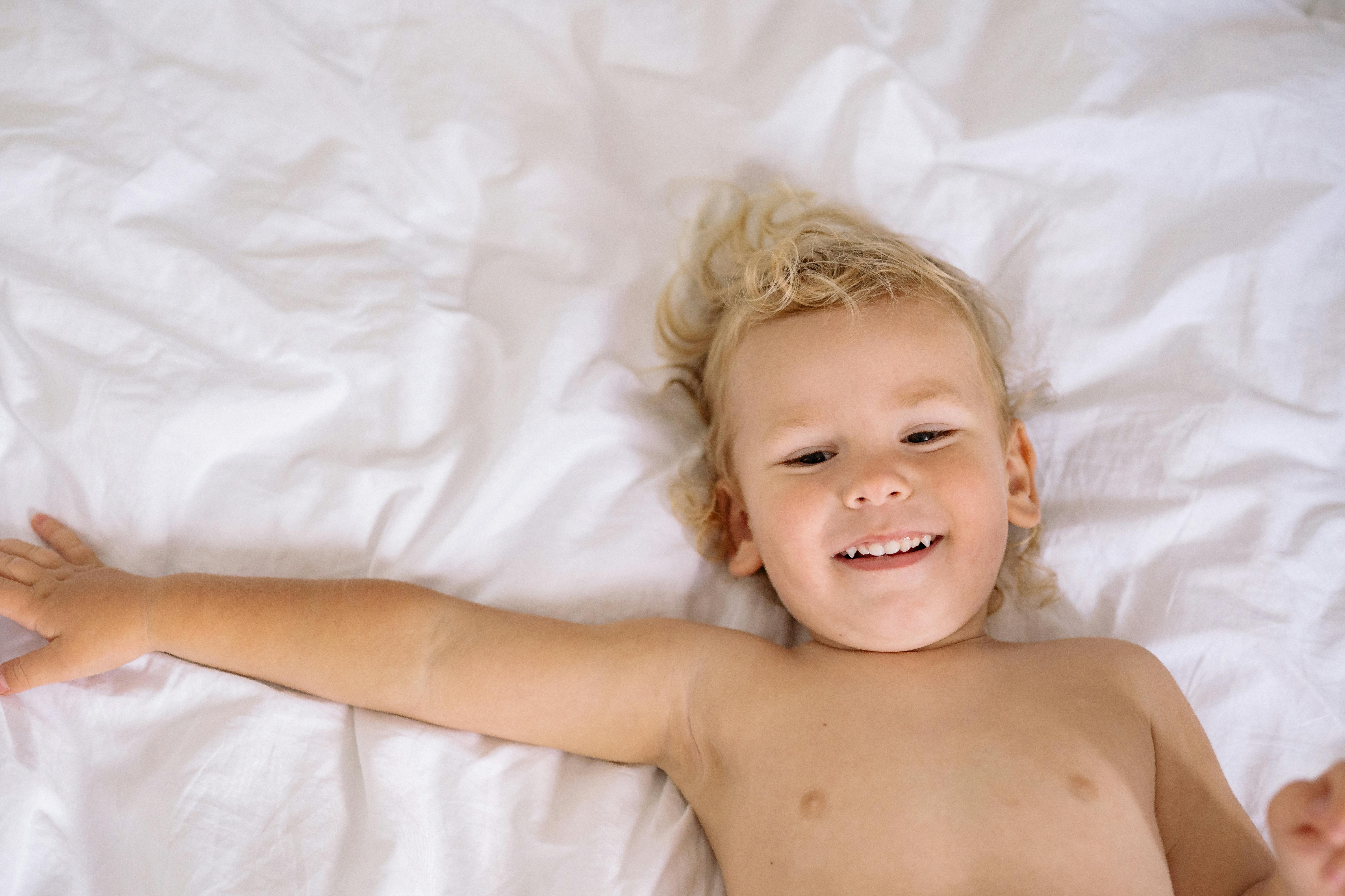 top view of smiling child lying on bed