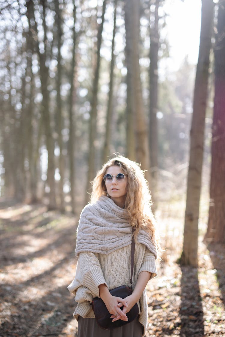 Woman In A Forest In Autumn Wearing A Sweater And Sunglasses