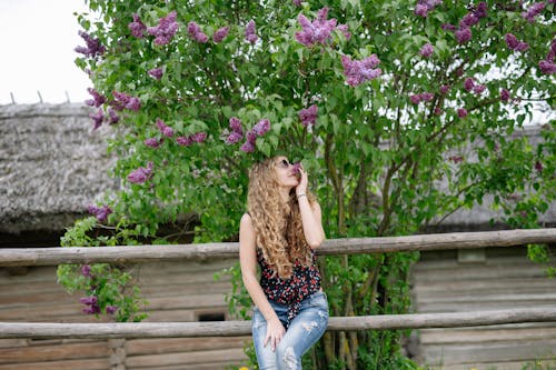 Free Woman in Black Tank Top and Blue Denim Jeans Sitting on Brown Wooden Bench Stock Photo