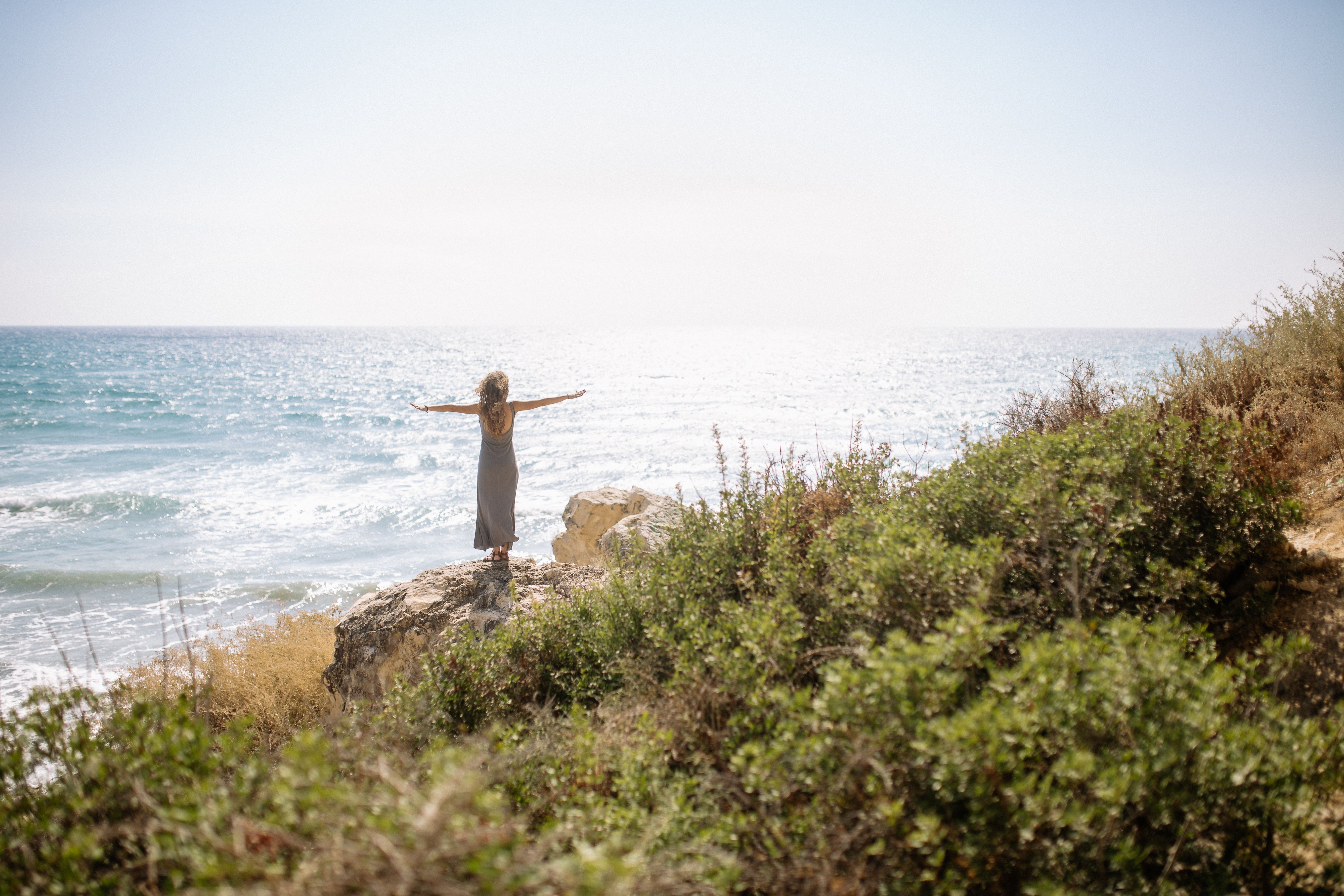 Woman in Dress Standing on Rock Near Body of Water · Free Stock Photo