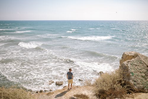 Free A Man Standing on a Cliff Looking Sideways Stock Photo