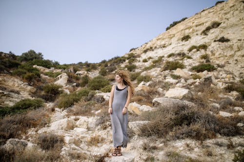 Free A Woman in Gray Dress Standing on a Rock Stock Photo