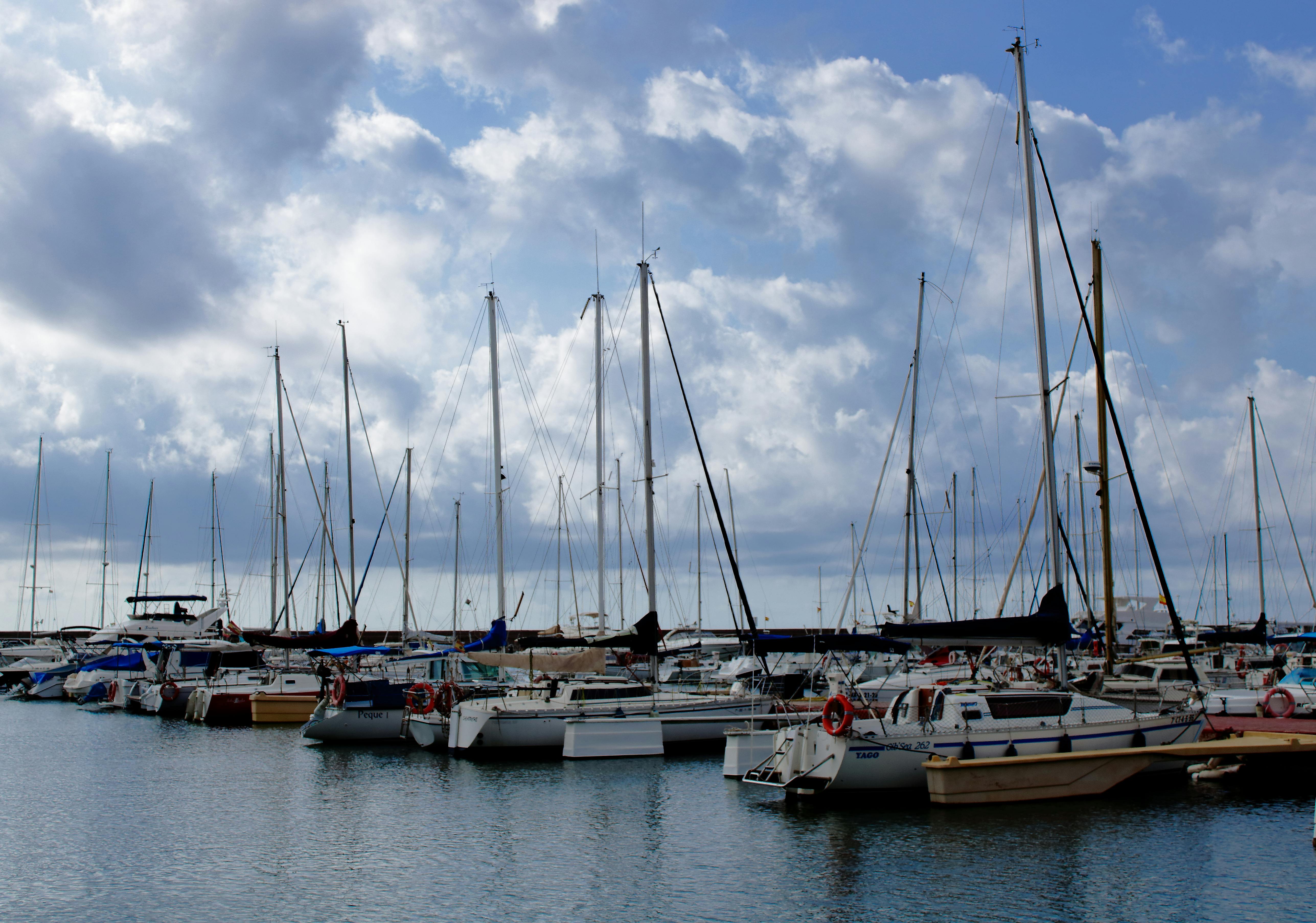 white clouds above anchored sailboats at a harbor