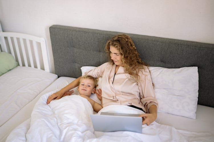 A Toddler Lying Next To Her Mother