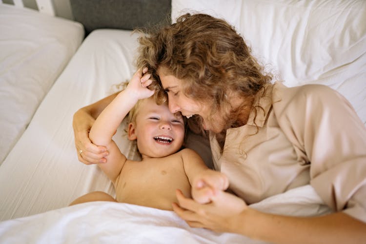 Woman And A Baby Laughing In The Bed