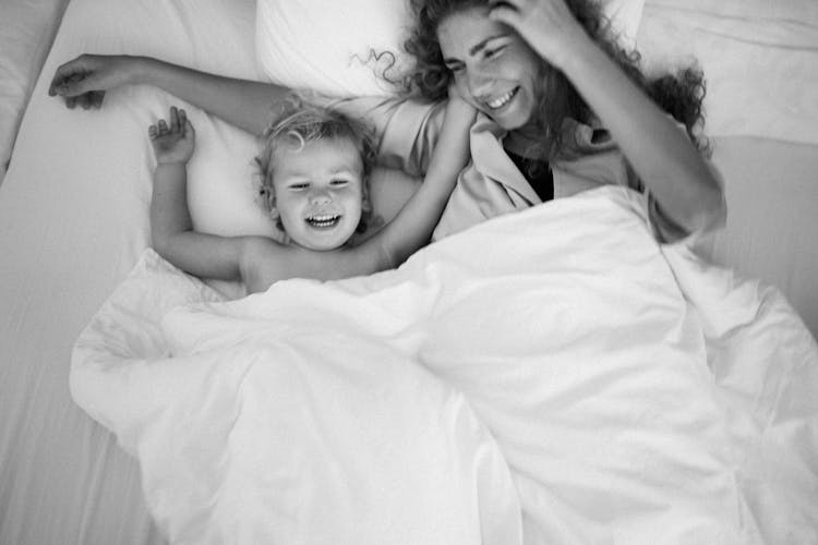 Woman And Her Son Lying In Bed And Laughing