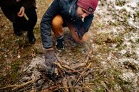 Man in Black Jacket and Red Knit Cap Sitting on Brown Dried Leaves