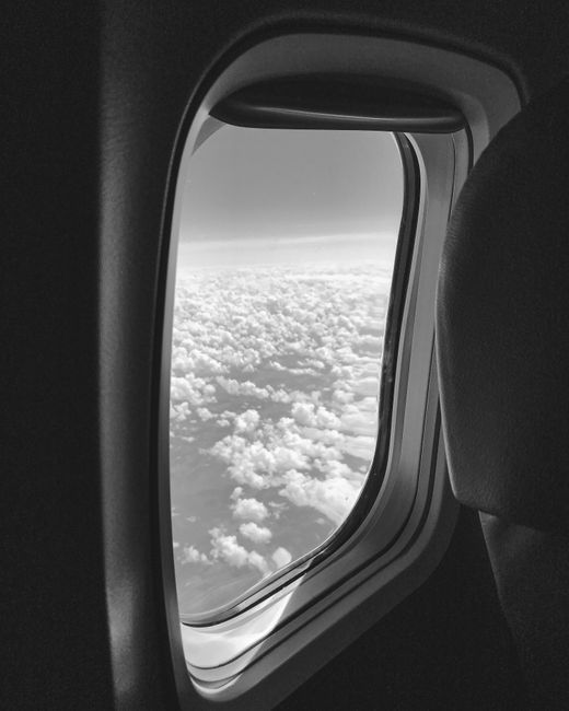 Grayscale view of clouds from an airplane window, showcasing the serenity of aerial travel.