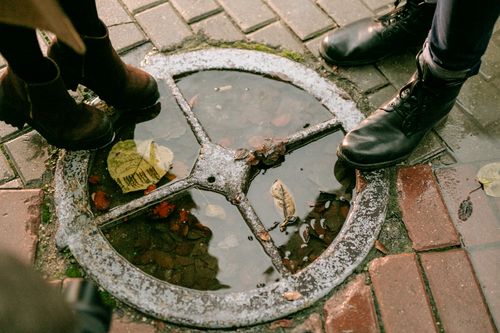 Free Close-up of boots around a puddle with autumn leaves on a wet street. Stock Photo