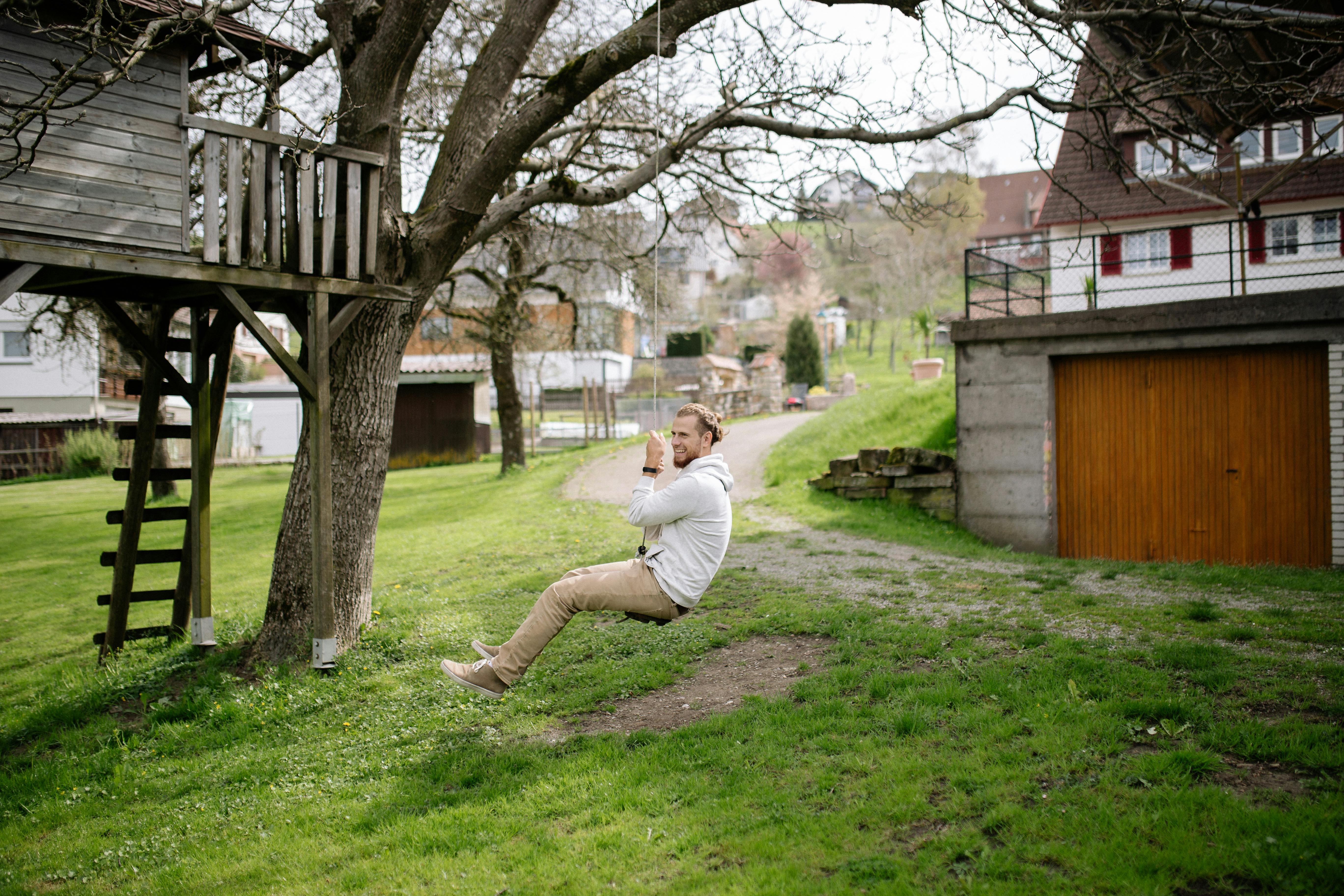 a man sitting on the swing under the tree