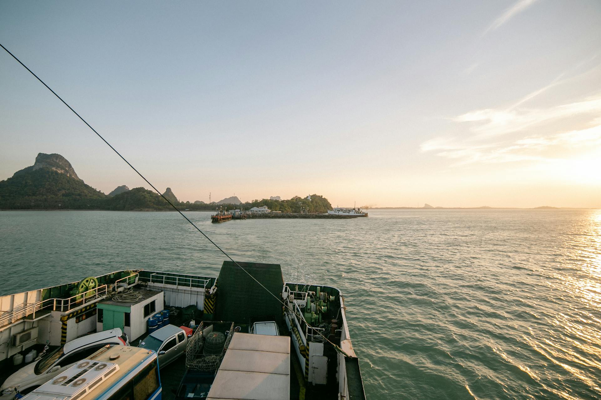 A tranquil ferry journey over calm waters, heading towards a distant island as the sun sets.
