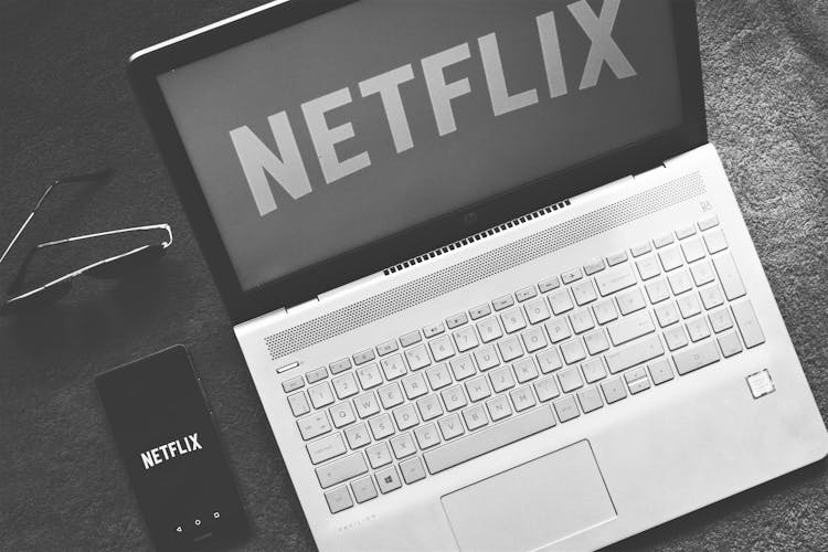 Netflix Logo On Smartphone And Laptop Screens