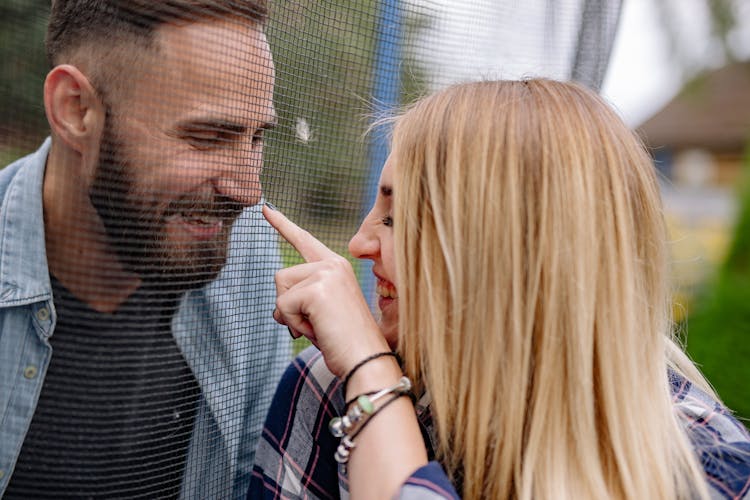 A Smiling Woman Pointing At A Man Behind A Net