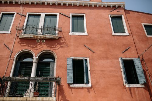 Free Vintage building facade with green shutters and ornate balcony in warm light. Stock Photo
