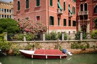 Red Boat on River Near Brown Concrete Building