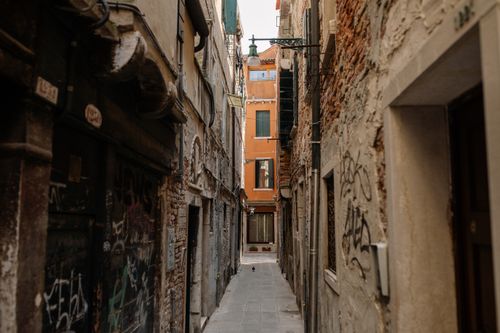 Free A narrow alleyway with old brick facades and graffiti in a historic city. Stock Photo