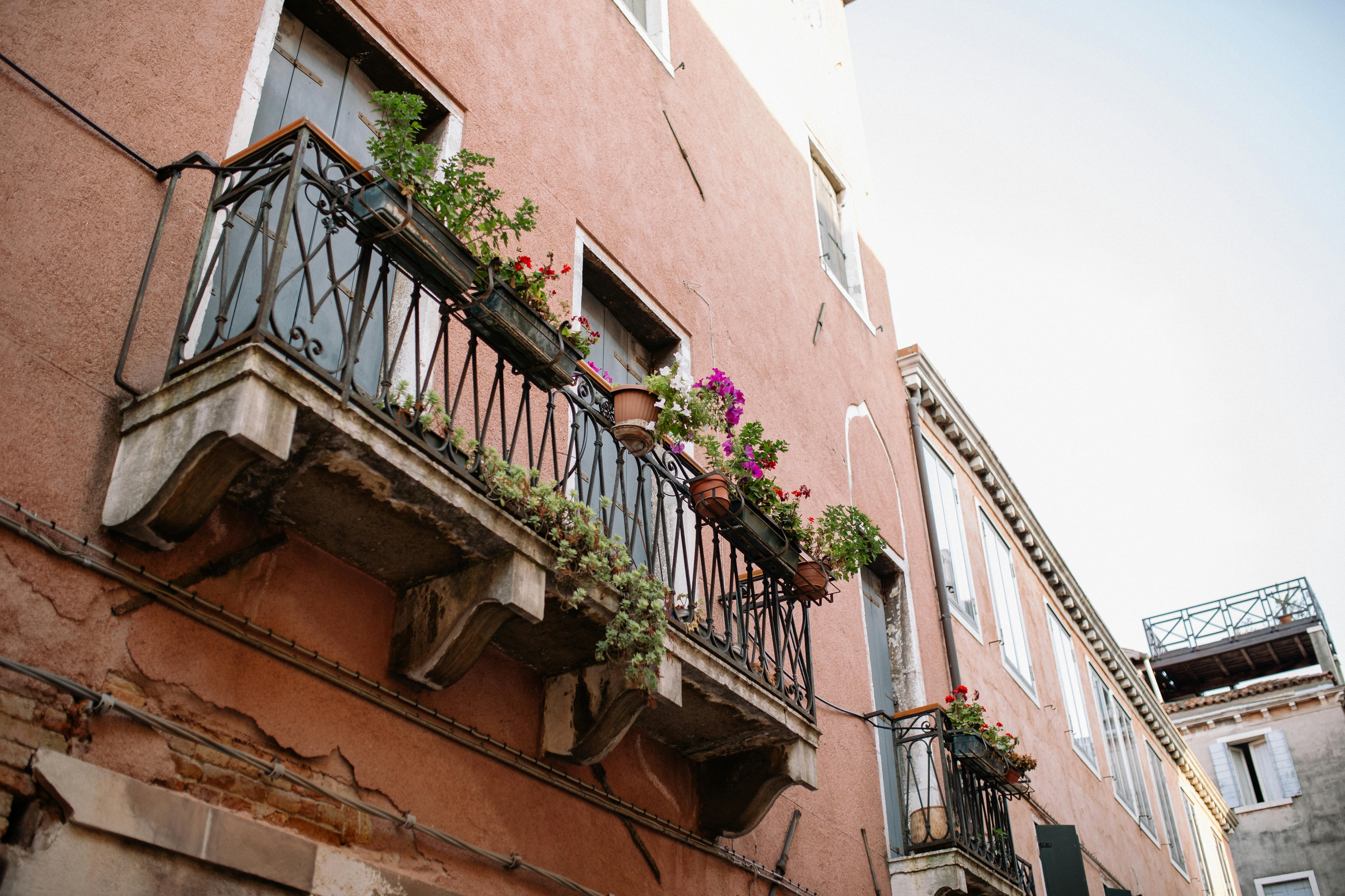 Rustic balconies adorned with vibrant floral arrangements on a Mediterranean townhouse.