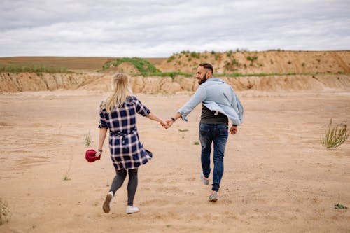 Free Couple Holding Hands and Walking on Beach Stock Photo