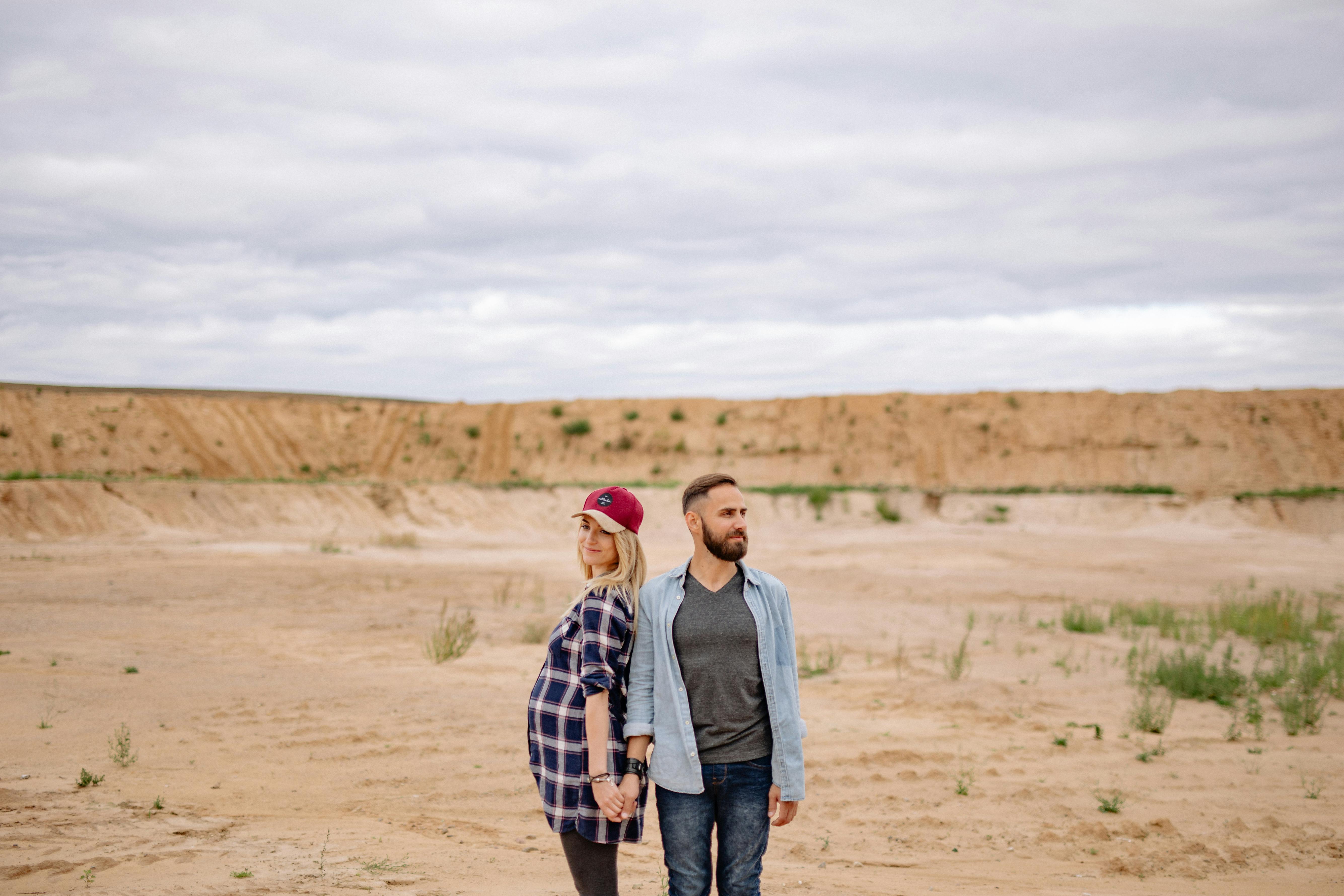 man and woman standing next to each other on the desert
