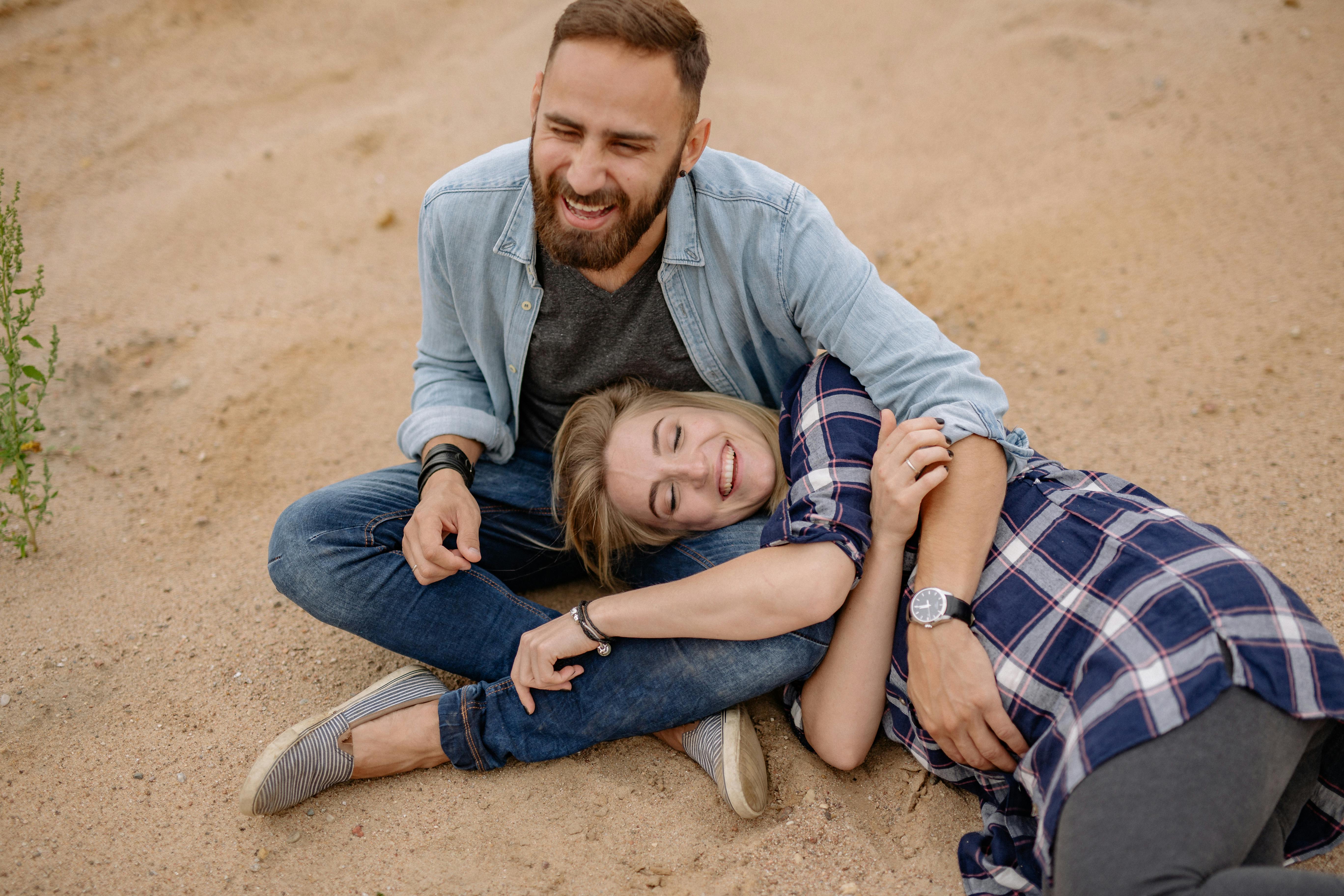 一对快乐的夫妇幸福地微笑着，紧紧相拥坐在沙滩上